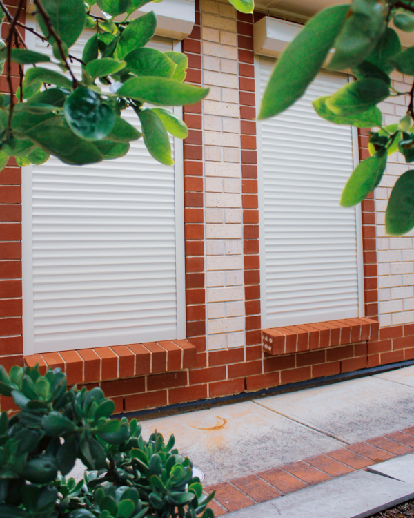 Residential roller shutters in a warm sunset light, adding a touch of elegance and security to a home exterior.